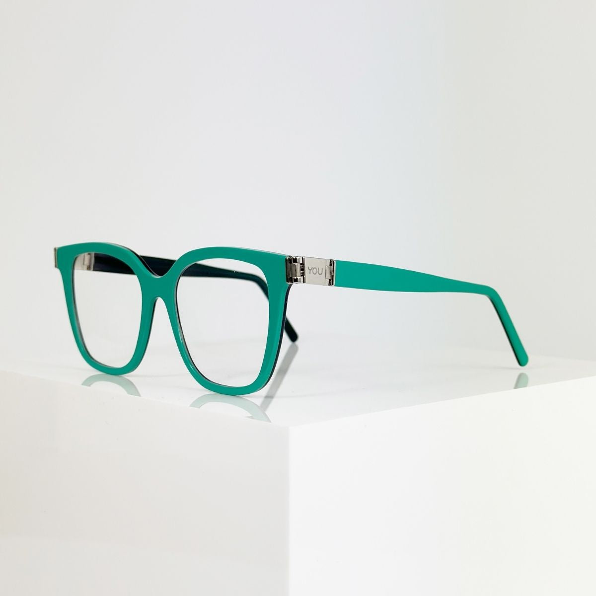 YQU Korrekturbrille mit drehbaren Bügeln, türkis-dunkelgrüner Acetat-Rahmen vor hellem Hintergrund